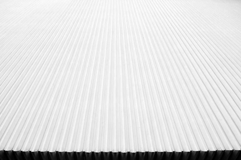 white-corrugated-board-904177 Abstract close-up of a modern corrugated metal roof with linear patterns in white.